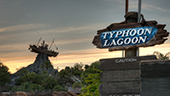 A life size sculpture of a shrimp boat impaled on a mountaintop stands in the background of a sign that reads Typhoon Lagoon
